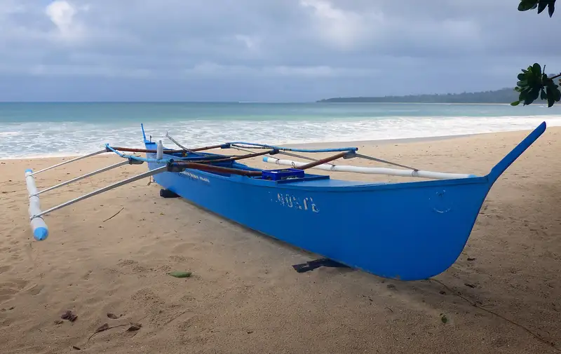 Traditional blue outrigger banca fishing boat on a Philippine beach