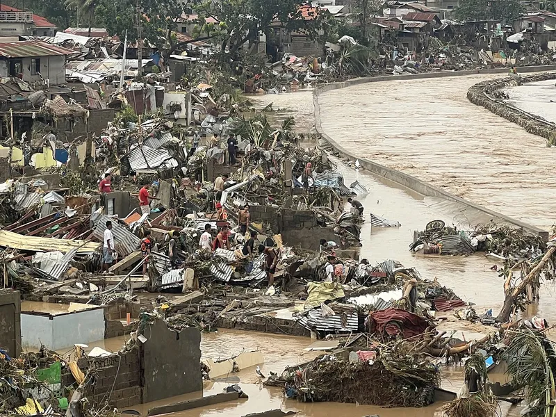 Residents sifting through debris beside the swollen Mananga River in Talisay, Cebu, after Typhoon Tino